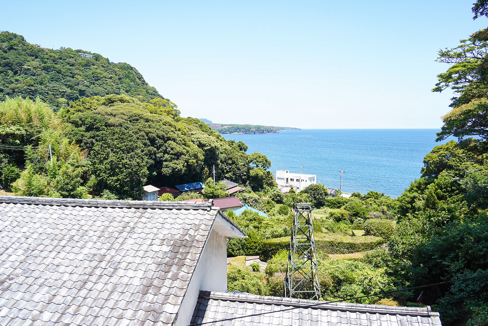 手前には、当館の自家源泉を汲み上げている温泉櫓が、写真中央には赤沢海岸、一番奥には城ヶ崎海岸が見えます。（客室401より）