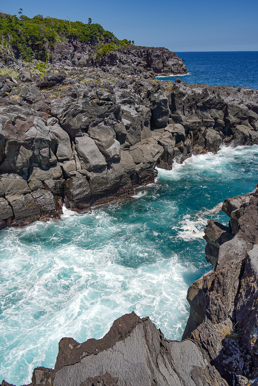 溶岩が固まったゴツゴツとした崖の合間から波が打ちつける轟音が聞こえます。