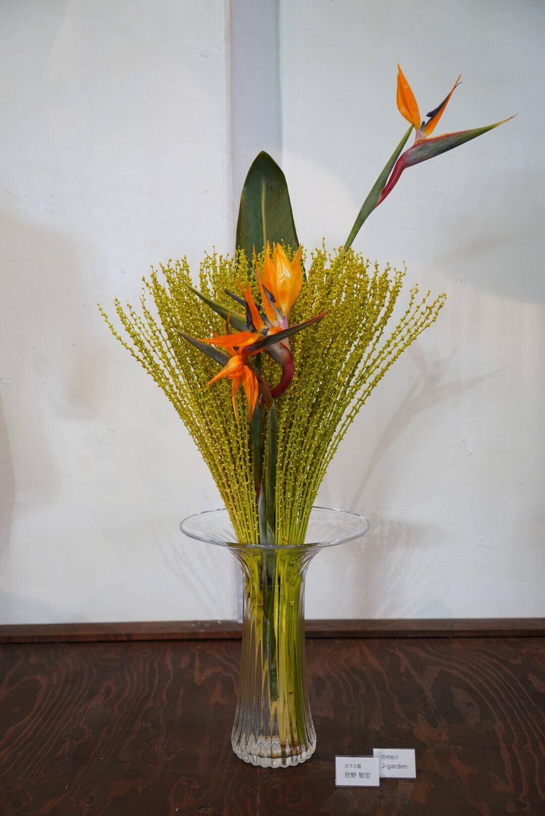 有名ガラス造形作家・狩野智宏氏の花器に、極楽鳥花と珍しいヤシの花で生けた作品。